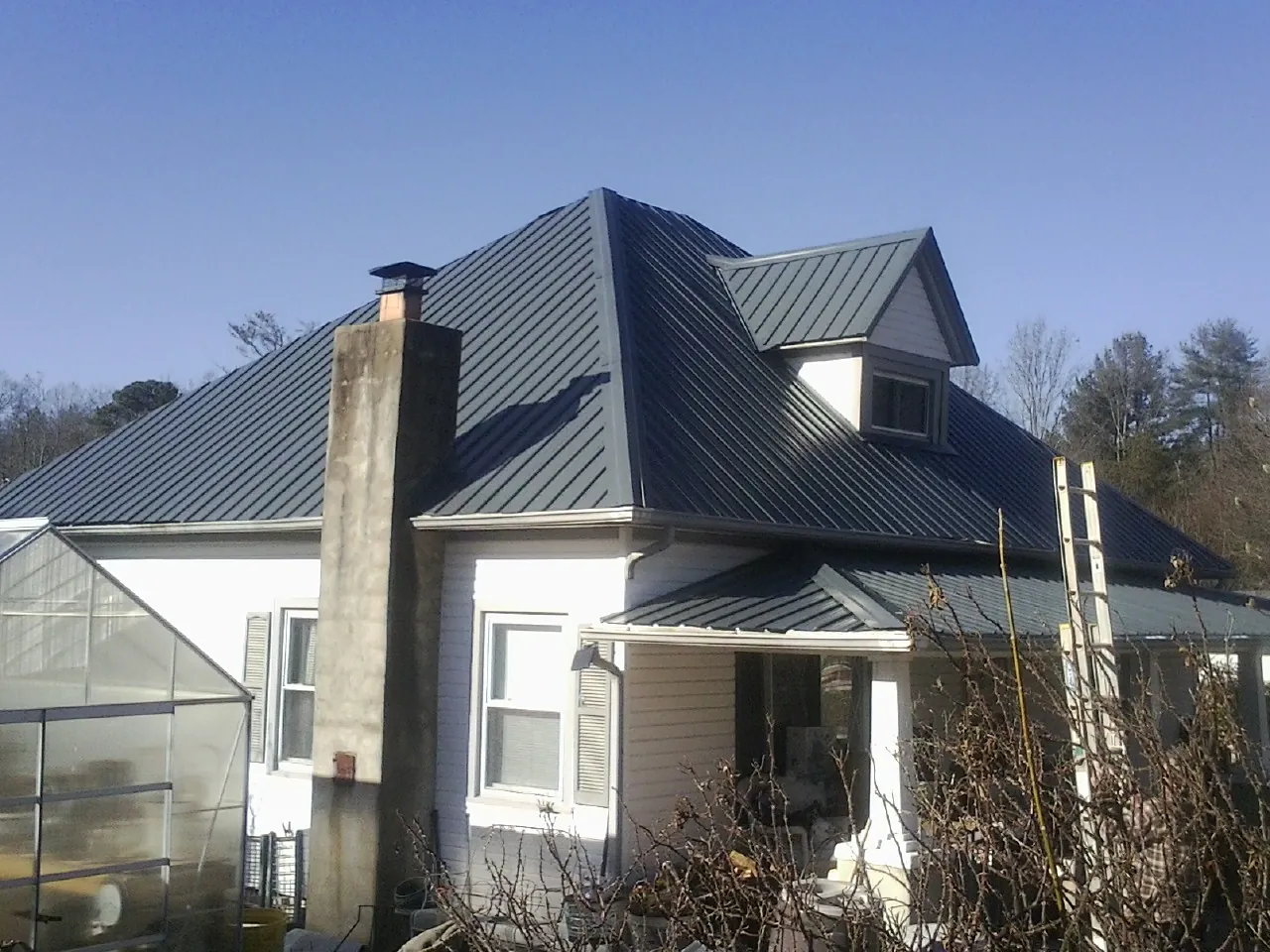 Dark blue standing seam metal roof on a white farmhouse with dormer — Slate & Tile Roof Repair by Roofing Brothers in Pleasant Ridge