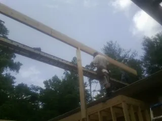 Carpenter setting a ridge beam over a new addition frame — Ice Dam Removal by Roofing Brothers in Pleasant Ridge