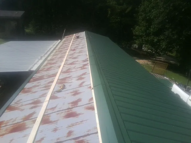 Old rusted panels beside newly installed green metal roofing — Wind Damage Roof Repair by Roofing Brothers in Pleasant Ridge