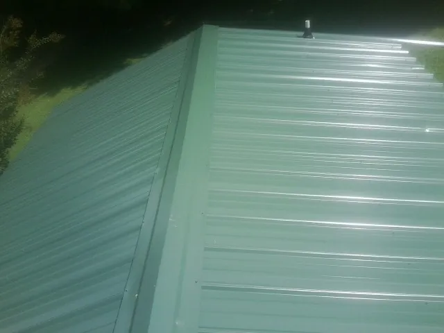 New green metal panels meeting at the ridge of a roof — Flat Roof Repair work by our crew in Pleasant Ridge