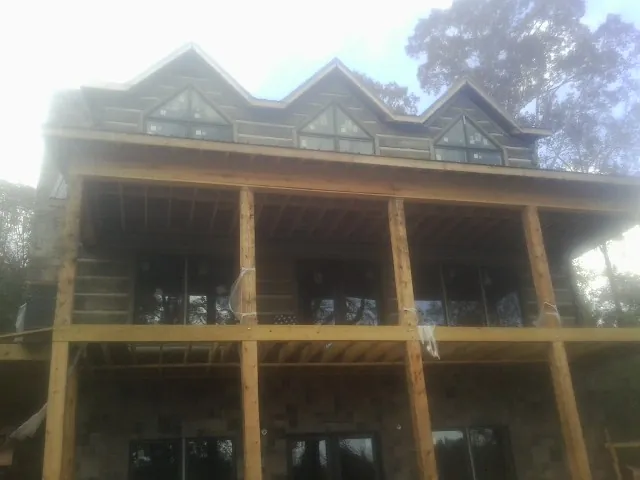 Dormers and porch framing on a large log home under construction — Roof Coating work by our crew in Pleasant Ridge