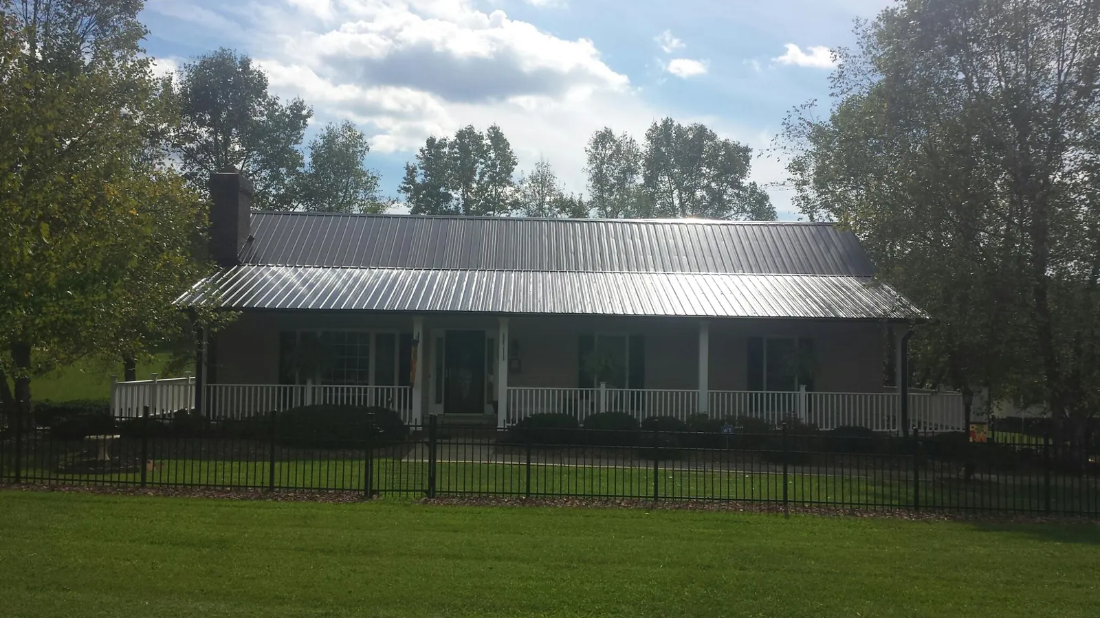 Gray metal roof on a brick ranch with a full width front porch — Gutter Guard Installation work by our crew in Pleasant Ridge