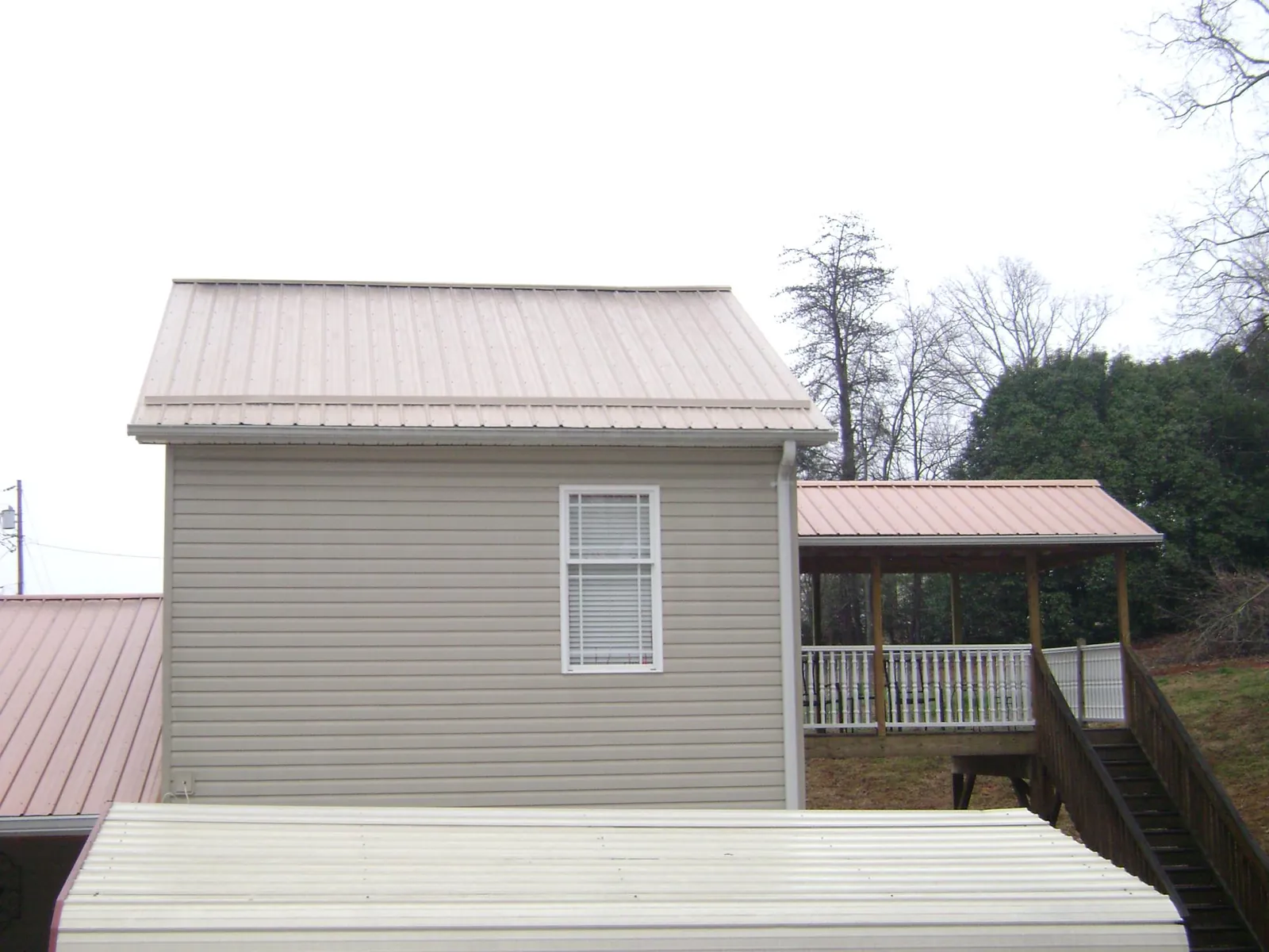 Tan metal roofs on a two story addition and attached porch, from a Roof Replacement job in Pleasant Ridge