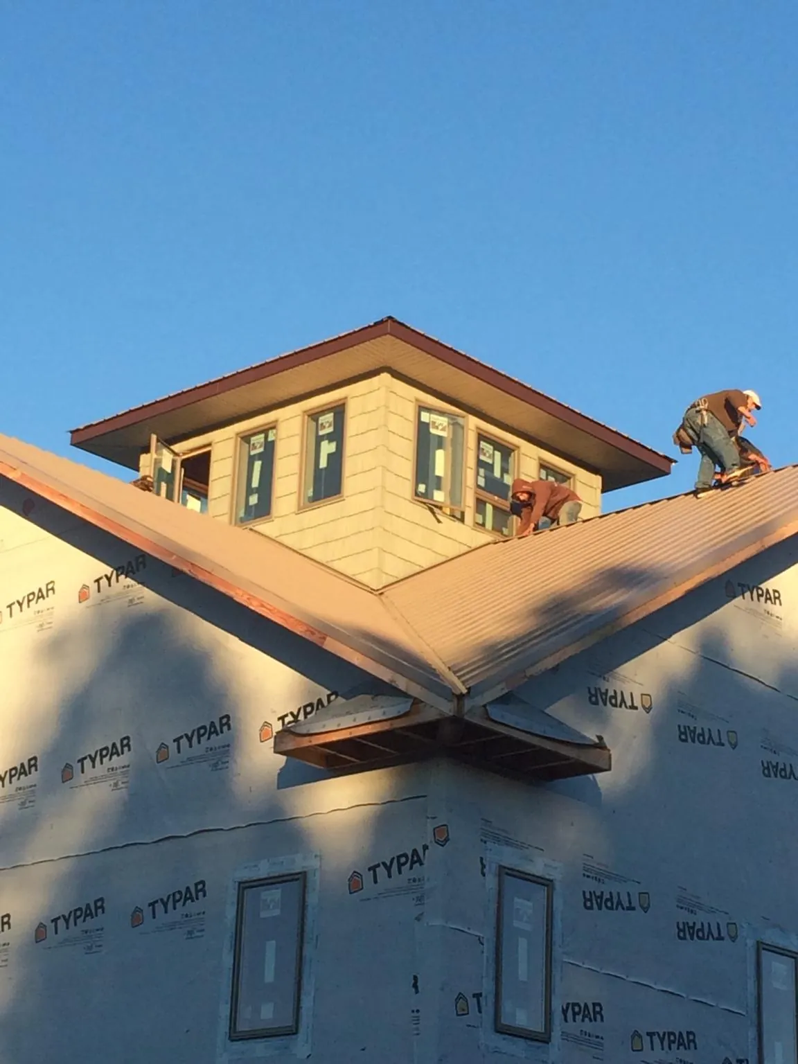 Roofers working around a rooftop cupola on a new metal roof at sunset — Roof Waterproofing in Pleasant Ridge by Roofing Brothers